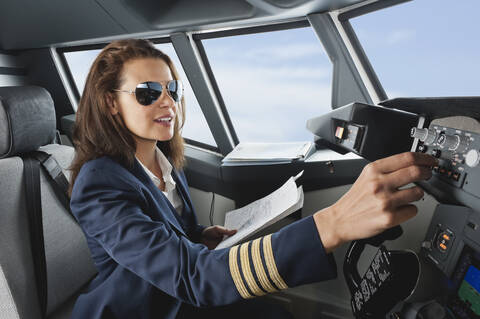 Deutschland, Bayern, München, Frau Flugkapitän mit Karte im Cockpit eines Flugzeugs, lizenzfreies Stockfoto