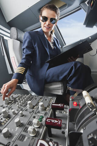 Deutschland, Bayern, München, Frau Flugkapitän steuert Flugzeug aus dem Cockpit, lizenzfreies Stockfoto