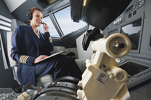 Deutschland, Bayern, München, Frau Flugkapitän steuert Flugzeug aus dem Cockpit - WESTF017035