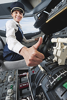 Germany, Bavaria, Munich, Woman flight captain with thumbs up in airplane cockpit - WESTF017040