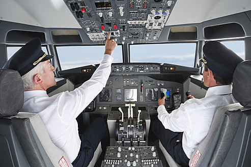 Germany, Bavaria, Munich, Pilot and co-pilot piloting aeroplane from airplane cockpit - WESTF017073