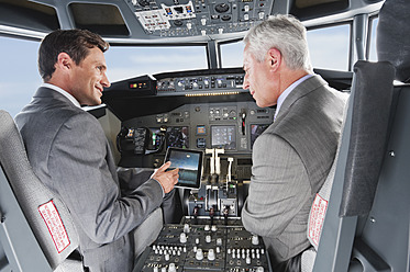 Deutschland, Bayern, München, Geschäftsleute zeigen digitale Tabelle im Cockpit eines Flugzeugs - WESTF017079