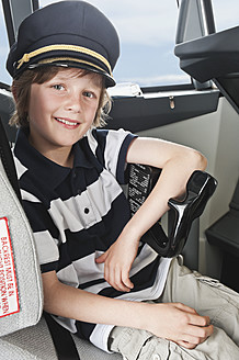 Germany, Bavaria, Munich, Boy wearing captain's hat and playing in airplane cockpit - WESTF017091