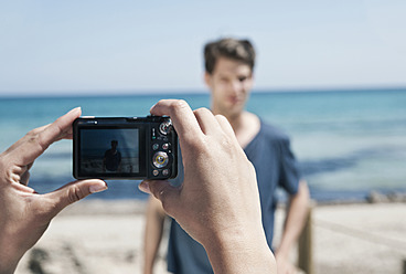 Spain, Majorca, Young woman taking picture of man at beach - WESTF017129