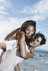 Spanien, Mallorca, Junger Mann trägt Frau auf dem Rücken am Strand - WESTF017135