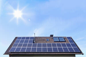 Germany, Solar panels on houseroof in front of blue sky with sun - TSF000345