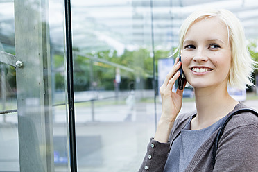 Deutschland, Bayern, München, Junge Frau mit Mobiltelefon, lächelnd - SPOF000041