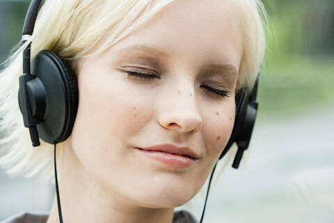 Deutschland, Bayern, München, Junge Frau hört Musik, lizenzfreies Stockfoto