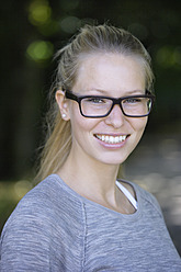Deutschland, Bayern, Schaeftlarn, Junge Frau mit dickrandiger Brille, lächelnd, Porträt, Nahaufnahme - TCF001713