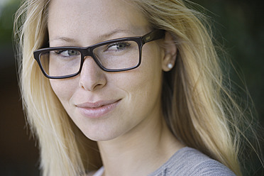 Deutschland, Bayern, Schaeftlarn, Junge Frau mit dickrandiger Brille, lächelnd, Nahaufnahme - TCF001730