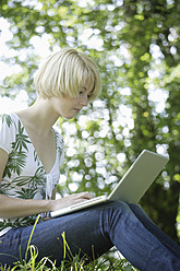 Germany, Bavaria, Schaeftlarn, Young woman using laptop in park - TCF001772