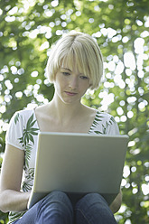 Deutschland, Bayern, Schaeftlarn, Junge Frau mit Laptop im Park - TCF001773