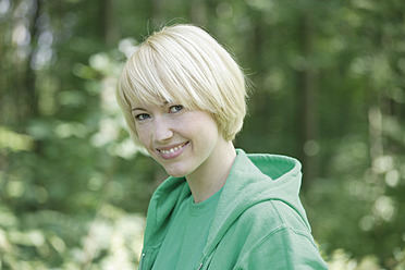 Deutschland, Bayern, Schaeftlarn, Nahaufnahme einer jungen Frau im Wald, Porträt, lächelnd - TCF001779