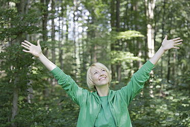 Germany, Bavaria, Schaeftlarn, Young woman in forest with arms up, smiling - TCF001777