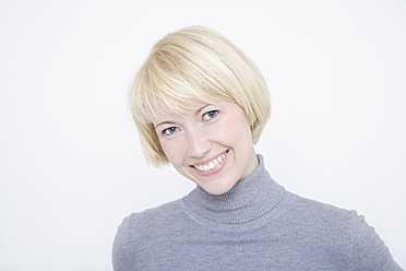 Close up of young woman against white background, portrait, smiling - TCF001764