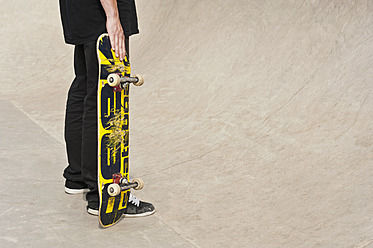 Germany, Duesseldorf, Man holding skateboard in public skate park - KJF000151