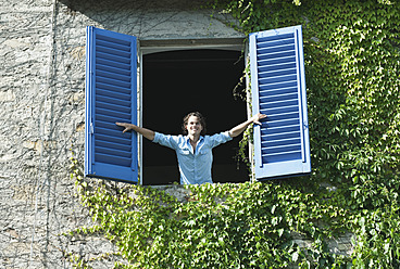 Italien, Toskana, Junger Mann lehnt an Fenster mit Fensterläden - PDF000184