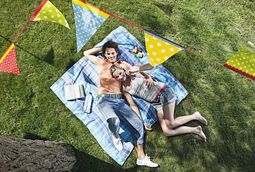 Italien, Toskana, Junges Paar auf Picknickdecke liegend mit Essen und darüber hängender Fahnenleine - PDF000193
