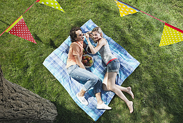 Italien, Toskana, Junges Paar auf Picknickdecke liegend mit Essen und darüber hängender Fahnenleine - PDF000195