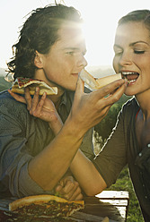 Italien, Toskana, Junges Paar füttert sich gegenseitig mit Pizza in der Abenddämmerung - PDF000203