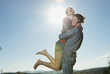 Italy, Tuscany, Young man carrying woman on his back against sun - PDF000224