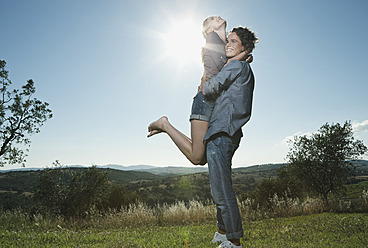 Italy, Tuscany, Young man carrying woman on his back against sun - PDF000225