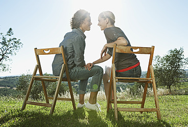 Italy, Tuscany, Young couple sitting together on wooden chairs - PDF000226