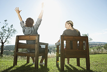 Italy, Tuscany, Young couple sitting together on wooden chairs - PDF000227