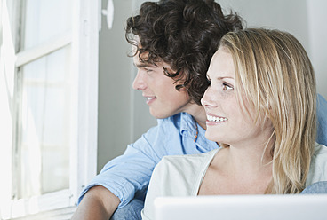 Italy, Tuscany, Young couple sitting with laptop on stairway of hotel - PDF000249