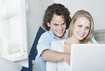 Italy, Tuscany, Young couple sitting with laptop on stairway of hotel - PDF000250