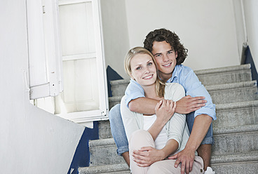 Italy, Tuscany, Young couple sitting on stairway of hotel, portrait - PDF000252