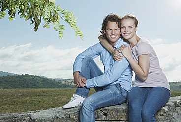 Italien, Toskana, Junges Paar sitzt auf Steinmauer - PDF000288