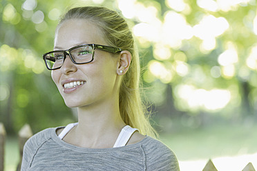 Deutschland, Bayern, Schaeftlarn, Nahaufnahme einer jungen Frau mit dicker Brille, lächelnd - TCF001750