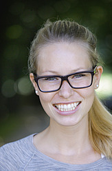 Germany, Bavaria, Schaeftlarn, Close up of young woman with thick spectacles, portrait, smiling - TCF001749