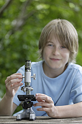 Deutschland, Bayern, Ebenhausen, Junge mit Mikroskop, lächelnd, Porträt - TCF001802