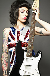 Young woman with guitar and tattoo on her hand against grey background - MBE000181