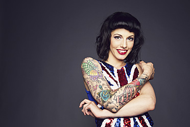 Young woman with tattoo on her hand against grey background - MBE000189