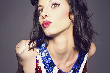 Young woman with tattoo on her hand pouting against grey background, close up - MBE000191