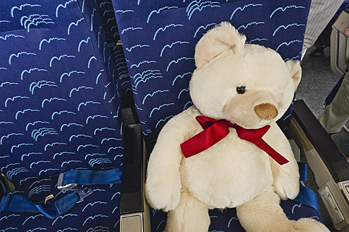 Deutschland, München, Bayern, Nahaufnahme eines Teddybären in der Economy Class eines Flugzeugs - WESTF017177