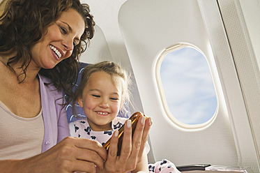 Deutschland, München, Bayern, Frau und Mädchen mit Mobiltelefon in der Economy Class eines Flugzeugs - WESTF017184