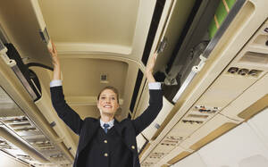 Deutschland, München, Bayern, Stewardess beim Schließen der Sicherheitsschließfächer in der Economy Class eines Flugzeugs - WESTF017205