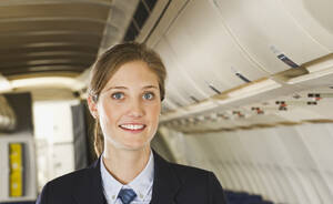 Deutschland, München, Bayern, Nahaufnahme einer Stewardess in der Economy Class eines Flugzeugs, lächelnd, Porträt - WESTF017206