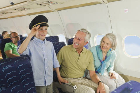 Germany, Munich, Bavaria, Boy wearing captains hat and people looking in economy class airliner stock photo