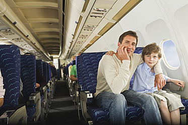 Deutschland, München, Bayern, Mann und Junge sitzen zusammen in der Economy Class eines Flugzeugs - WESTF017246