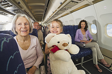 Deutschland, München, Bayern, Mädchen hält Teddybär in der Economy Class eines Flugzeugs - WESTF017248