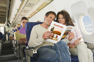 Deutschland, München, Bayern, Passagiere lesen ein Buch in der Economy Class eines Flugzeugs - WESTF017258