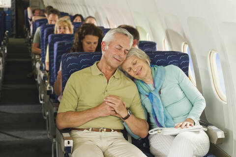 Deutschland, München, Bayern, Gruppe von Passagieren in der Economy Class eines Flugzeugs, lächelnd, lizenzfreies Stockfoto