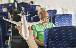 Deutschland, München, Bayern, Hand zeigt Flugzeugmodell in der Economy Class - WESTF017271