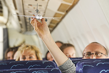 Germany, Munich, Bavaria, Hand showing aeroplane model in economy class airliner - WESTF017272