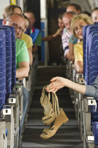 Deutschland, München, Bayern, Hände halten High-Heel-Sandalen in der Economy Class eines Flugzeugs - WESTF017274